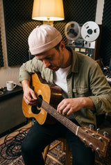 Müzik stüdyosunda bej docker şapka takarak gitar çalan erkek