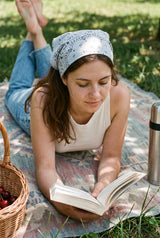 Piknikte buz mavisi desenli bandana takarak kitap okuyan kadın